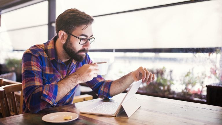 Man drinking coffee on computer at cafe